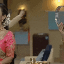 a woman in a pink blouse holds a plate in her hand