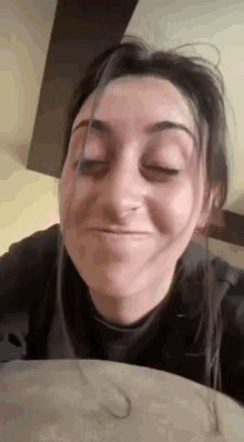 a woman is making a funny face while sitting on a couch with her eyes closed .