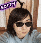 a woman wearing sunglasses has a sticker that says sorry