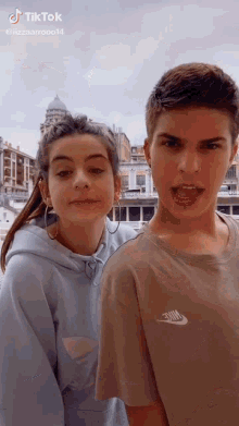 a boy and a girl are standing next to each other and making a funny face .