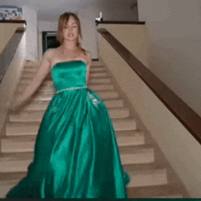 a woman in a green strapless dress is walking down stairs