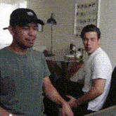 a man wearing a black hat and a green shirt is talking to another man