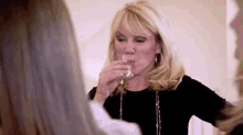 a woman is drinking a glass of wine while another woman watches .
