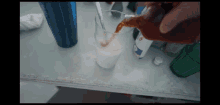 a person pouring a drink into a glass with a spoon in it
