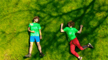 two boys laying on the grass with their shadows on the grass