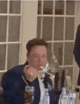 a man is sitting at a table with a spoon in his mouth .