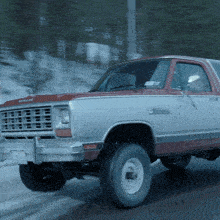 a silver and red dodge ram truck is driving down a snowy road