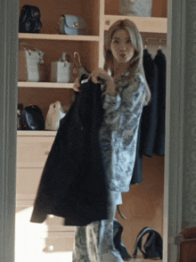 a woman is standing in a closet holding a jacket