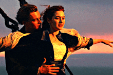 a man and a woman are standing next to each other with a sunset in the background