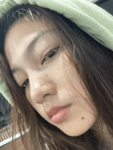 a close up of a woman 's face with a green towel on her head