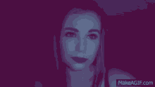 a woman is looking at the camera in a dark room with a purple background .