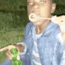 a young boy is blowing soap bubbles with a straw in his mouth .