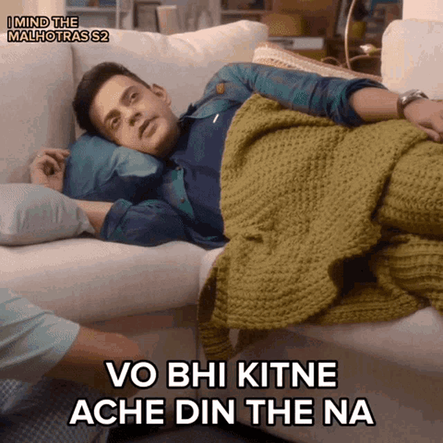 a man laying on a couch under a blanket with the words 