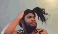 a man with a beard is holding a bunch of hair in his hand .