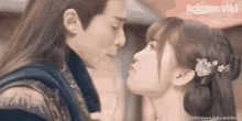 a man and a woman are kissing in front of a sign that says rakuten viki
