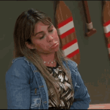 a woman in a denim jacket is sitting in front of a striped oar