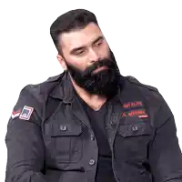 a man with a beard is wearing a black jacket that says army elite on it