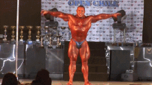 a bodybuilder stands in front of an open chile banner