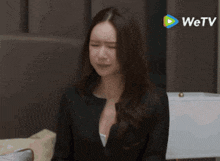 a woman is sitting in front of a wetv advertisement