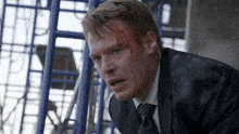 a man in a suit and tie with blood on his forehead