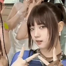 a close up of a woman 's face with a ponytail and a group of people behind her .