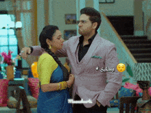 a man in a suit is standing next to a woman in a blue and yellow saree with a caption that says sukoop