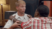 a man in a plaid shirt is talking to another man in a white shirt