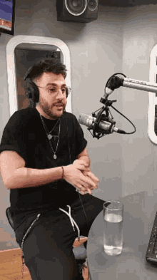 a man wearing headphones is sitting in front of a microphone with a glass of water on the table