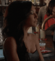 a woman is sitting at a bar with her eyes closed and her hand on her chest