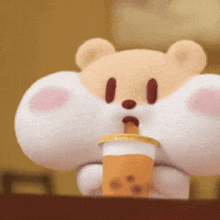a stuffed animal is drinking from a cup with a straw ..