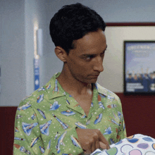 a man in a green shirt with rockets on it looks at something