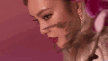 a close up of a woman 's face with a flower in the background .