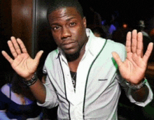 a man in a white shirt is holding his hands up