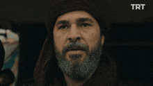 a man with a beard wearing a turban and a scarf with trt written on it
