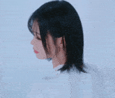 a woman in a white shirt is touching her hair and smiling
