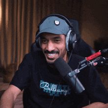 a man wearing headphones and a shirt that says balleany laughs in front of a microphone
