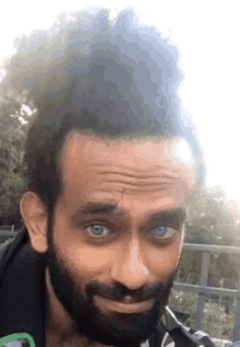 a man with a beard and blue eyes is making a funny face while looking at the camera .