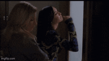 two women are standing next to each other in a room and one is screaming .