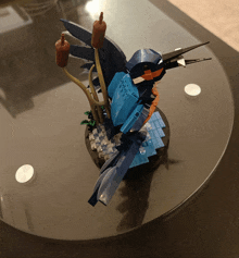 a blue and orange bird made out of lego sits on a table