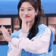 a woman in a blue jacket is making a peace sign with her hand