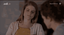 two women are sitting next to each other at a table and looking at each other .