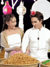 a man and a woman are standing next to a pile of food