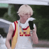 a young man with blonde hair is holding a napkin in his hand and blowing his nose .