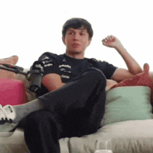 a man is sitting on a couch with his legs crossed and a shirt that says ' abarth ' on it