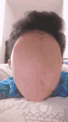 a person laying on a bed with a huge oval face