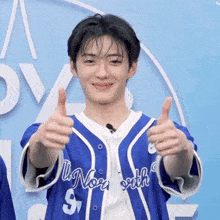 a young man in a blue and white jersey with the number 9 on it gives two thumbs up