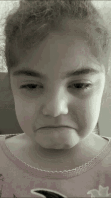 a little girl in a pink shirt is making a funny face