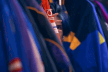 a young man with blue hair looks out from behind a row of jackets with one that says ' lacoste '