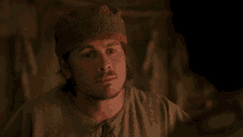a man wearing a red hat and a green shirt looks at another man