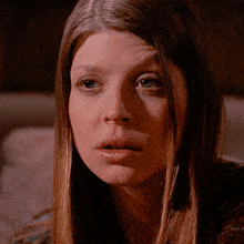 a close up of a woman 's face with brown hair and blue eyes